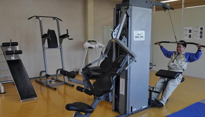 トレーニングジム器具で運動する社員